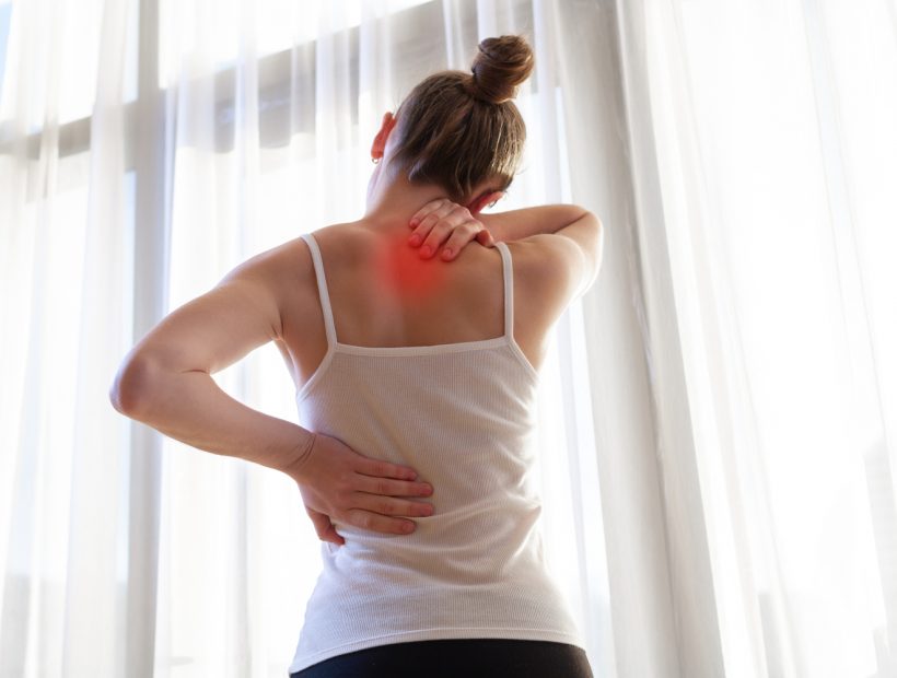 Young woman suffering from neck pain and backache, stretching the muscles at home. back and neck pain woman